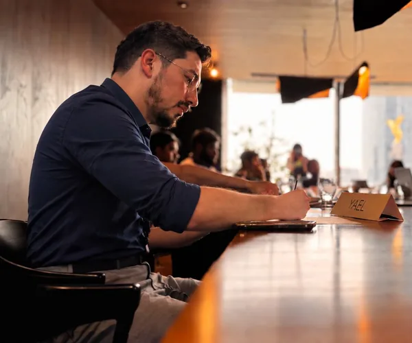 Yael Alvizuri escribiendo en una mesa larga durante una sesión de trabajo
